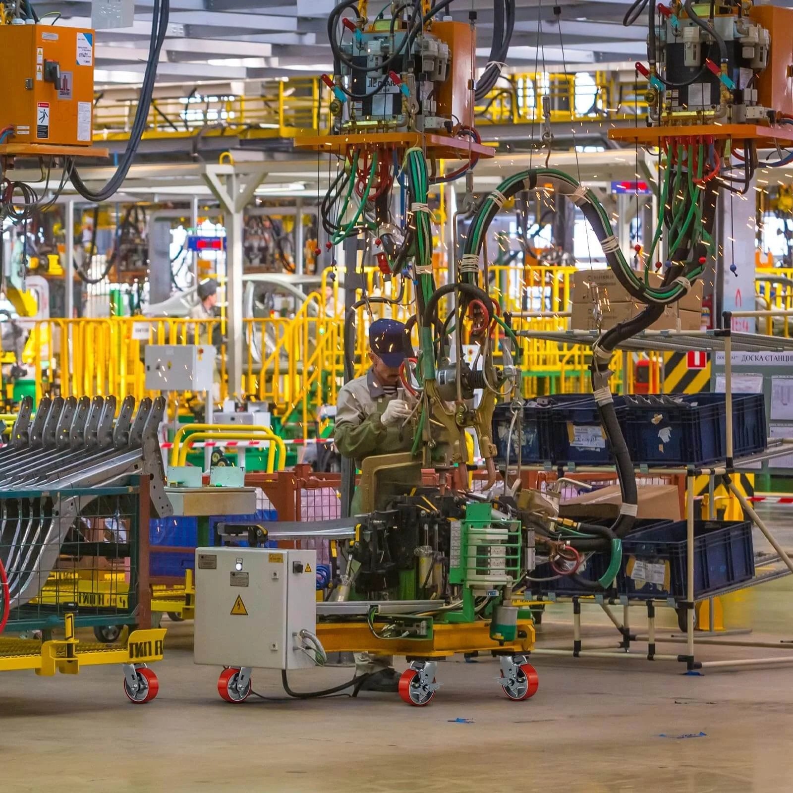 Industrial worker operating machinery in a busy factory with use of 5"x2" Industrial Casters- Heavy Duty casters for smooth movement.