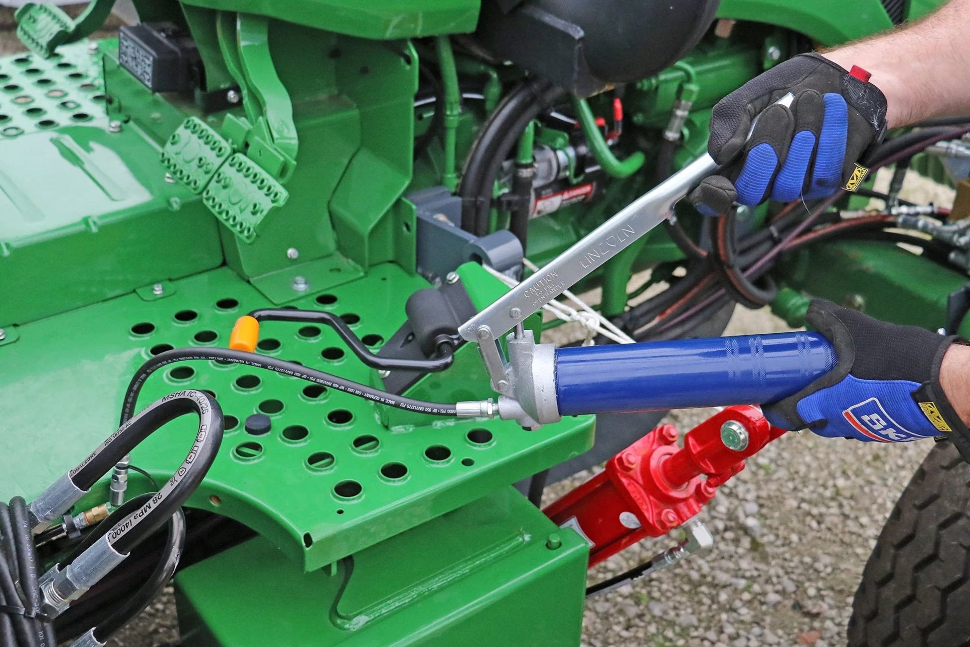 Person using Heavy Duty Lever Action Grease Gun With 18 Inch Whip Hose And Coupler, Jam Proof Toggle on farm machinery