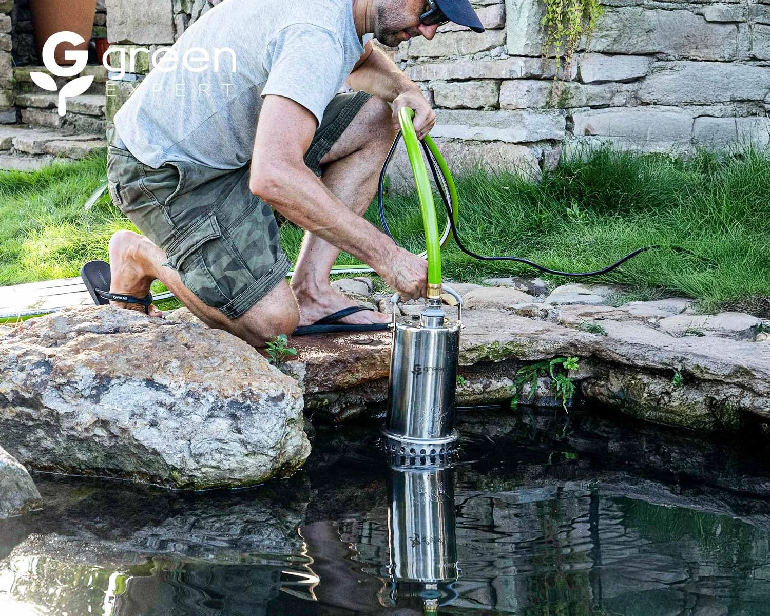 Person using 1 HP Submersible Sump Pump With 4000 GPH High Flow Green Expert Heavy Duty Full Stainless Steel Construction 25 Ft Power Cord Pro Grade Water Drainage For Flooded Basements Pools Ponds Hot Tubs And Rain Barrels beside a pond.