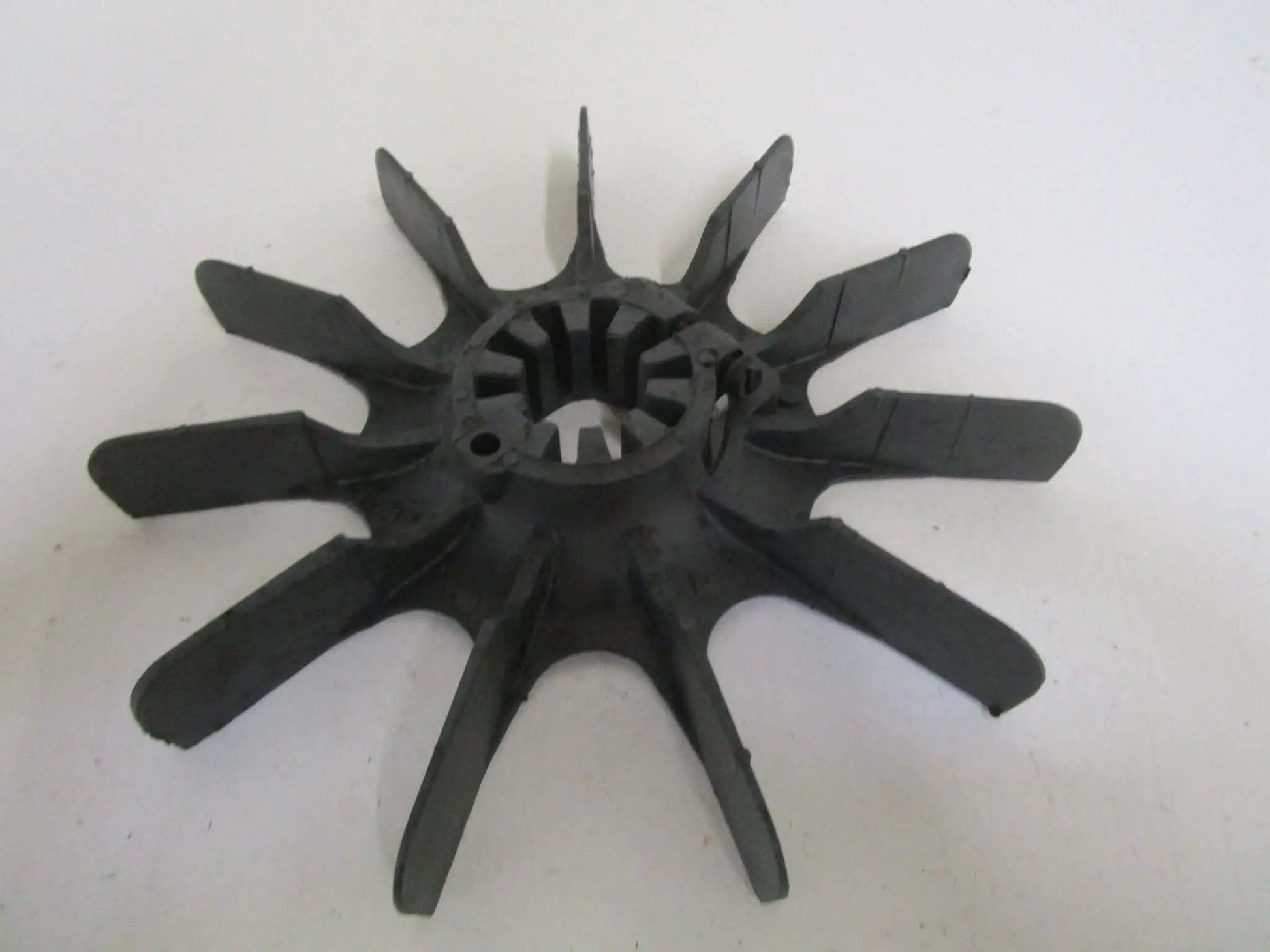 Plastic impeller fan with multiple blades, viewed from top angle, showing central hub and blade design details.