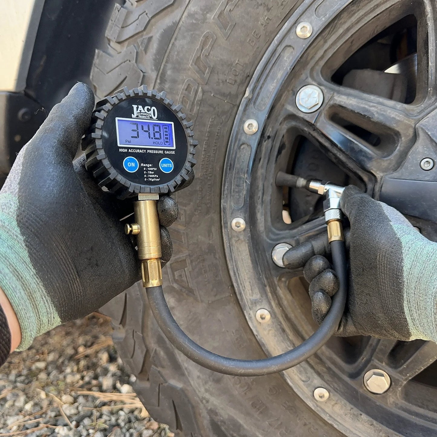Person using ElitePro Digital Tire Pressure Gauge Pro Grade Accuracy Up To 100 PSI With Dual Sensors Calibrated To ANSI 2A Standards 0.50 Percent FS 0.10 PSI Readout For Fast Cars Trucks Motorcycles And RV Tire Checks on a tire