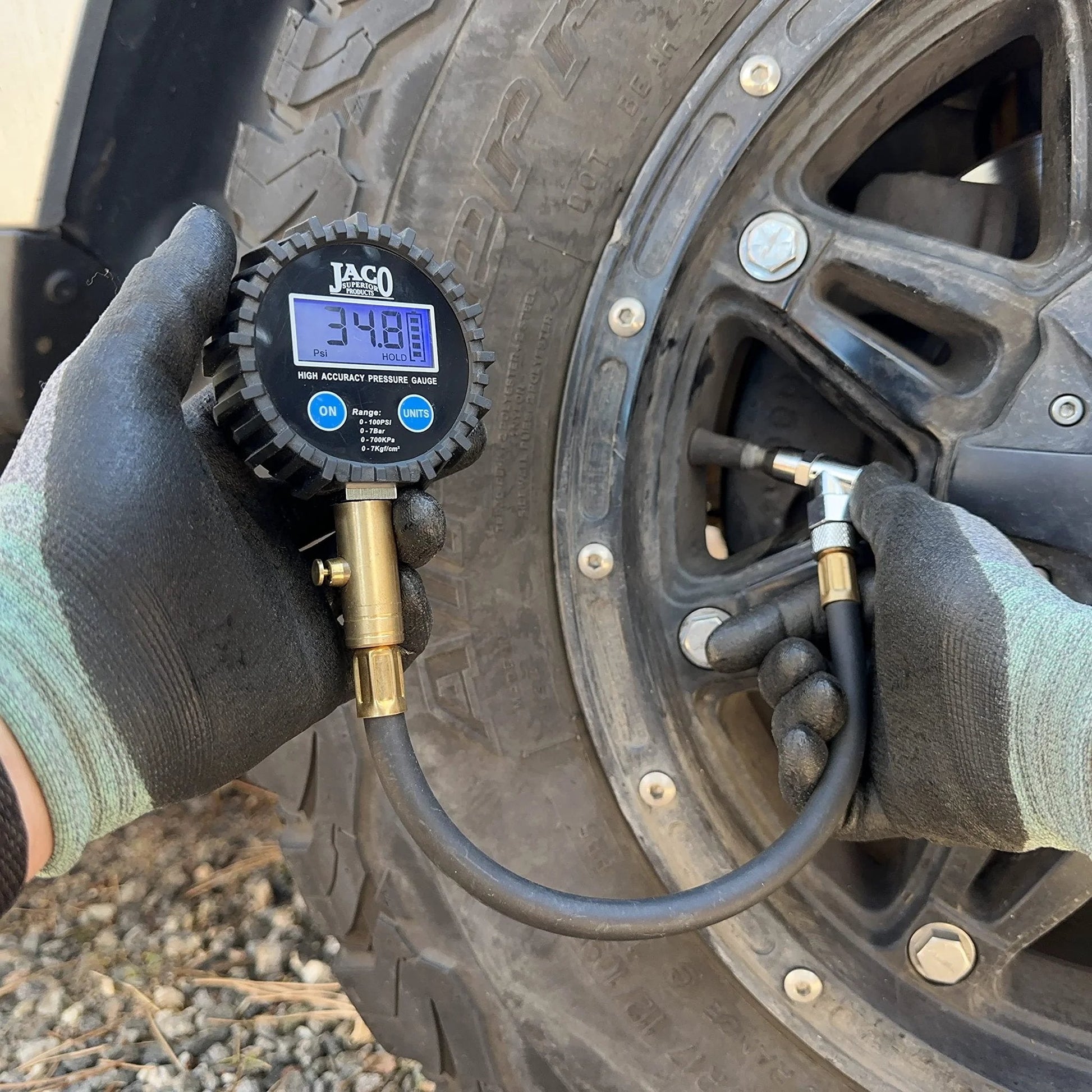 Person using ElitePro Digital Tire Pressure Gauge Pro Grade Accuracy Up To 100 PSI With Dual Sensors Calibrated To ANSI 2A Standards 0.50 Percent FS 0.10 PSI Readout For Fast Cars Trucks Motorcycles And RV Tire Checks on a tire