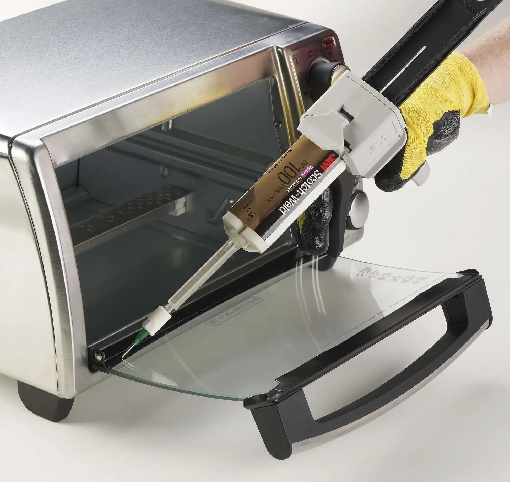 Applying 3M Scotch-Weld Clear Epoxy Adhesive DP100 Plus to an appliance glass door with a dispensing tool.