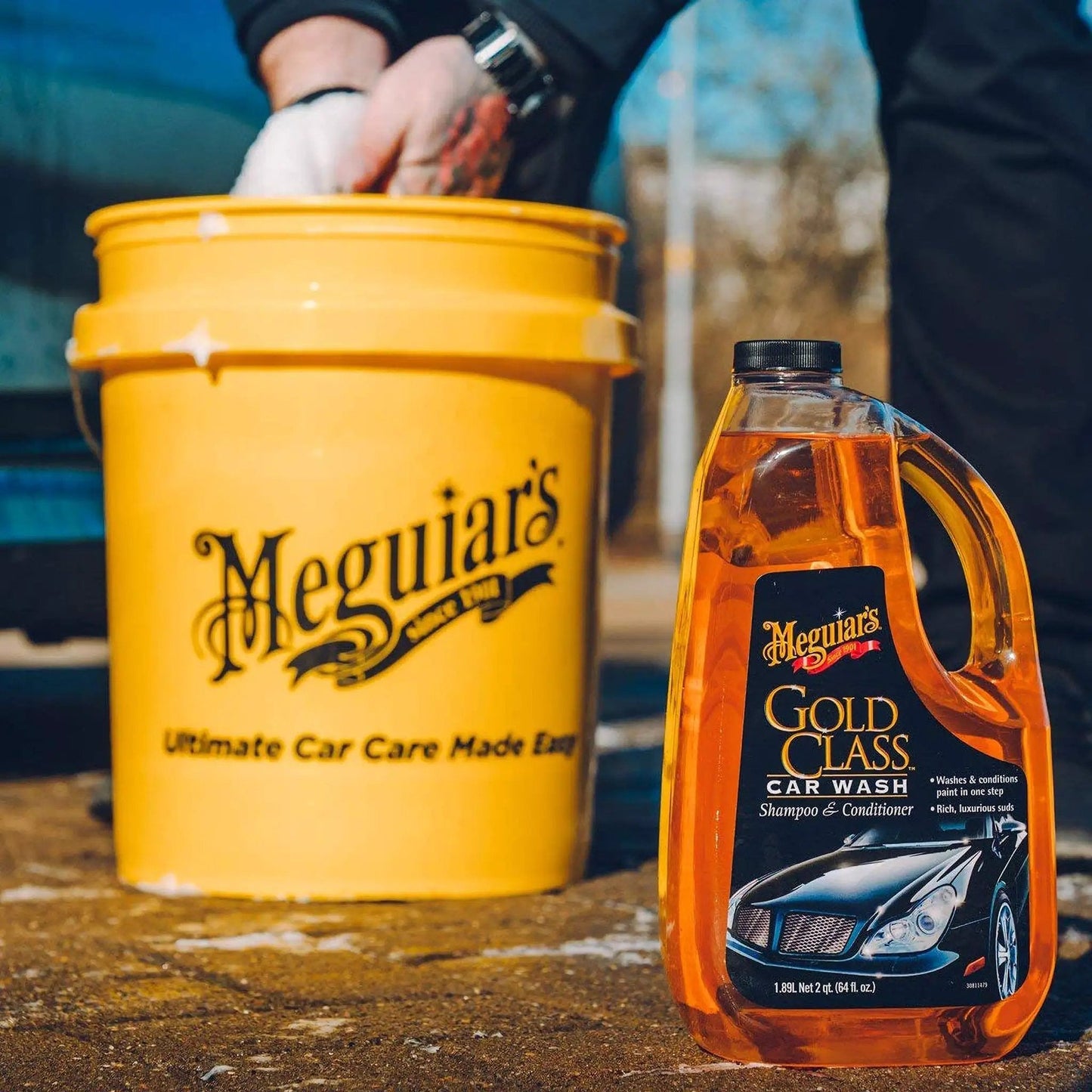Gold Class Car Wash Shampoo And Conditioner 64 Oz Meguiar's beside a yellow bucket for use in foam cannon or bucket wash.
