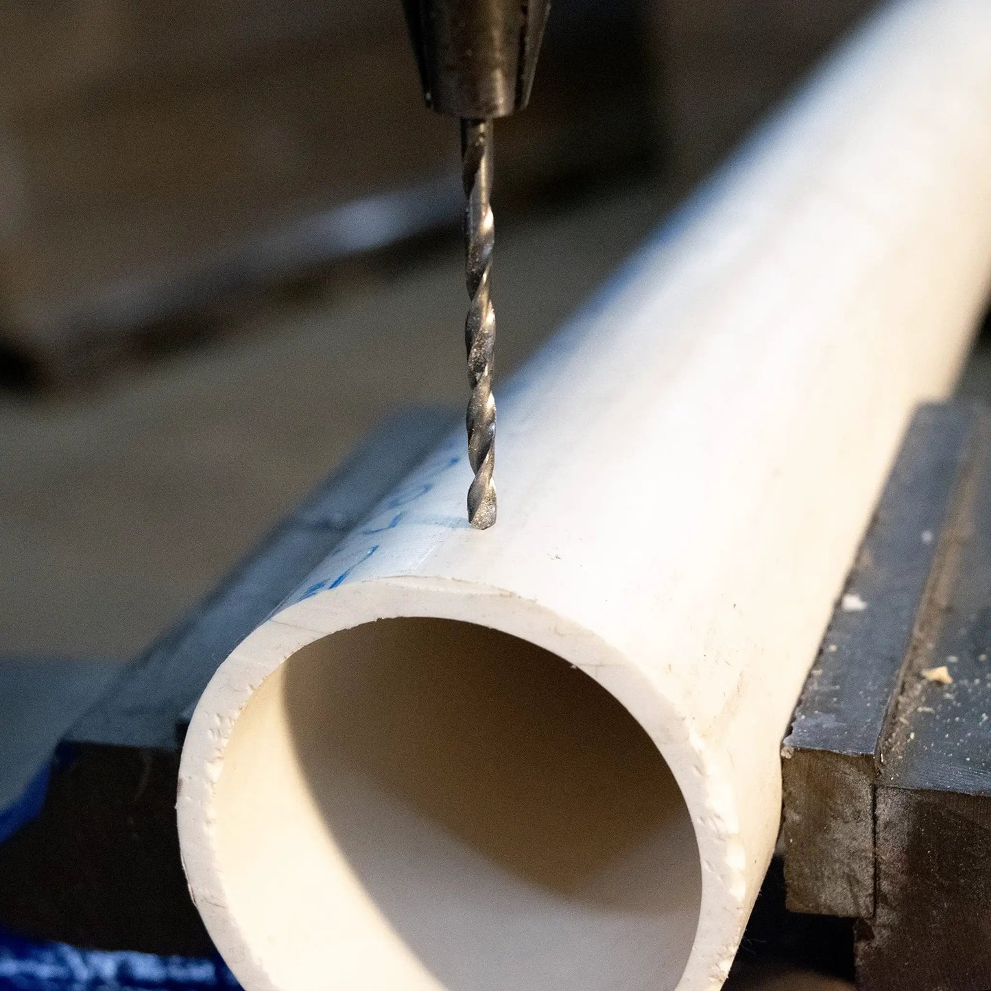 Premium High Speed Steel Wire Gauge Drill Bit No 44 drilling a hole in a PVC pipe, showcasing bright polished finish and precision.