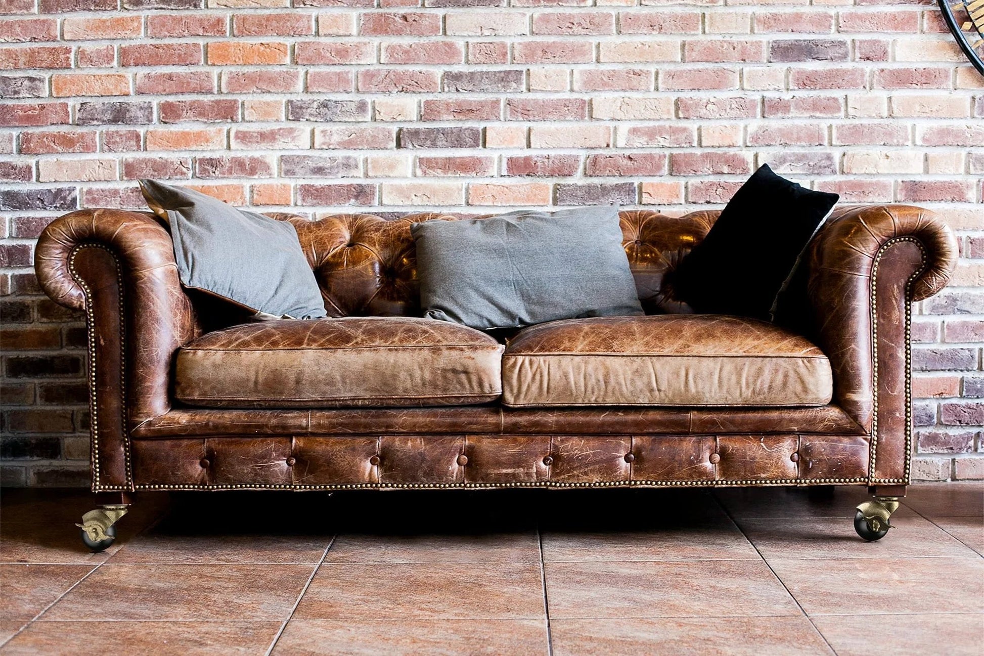 Brown leather sofa with 2 Inch Antique Brass Ball Casters Vintage Swivel Plate Caster Wheels with Brake Set of 4 installed, brick wall backdrop