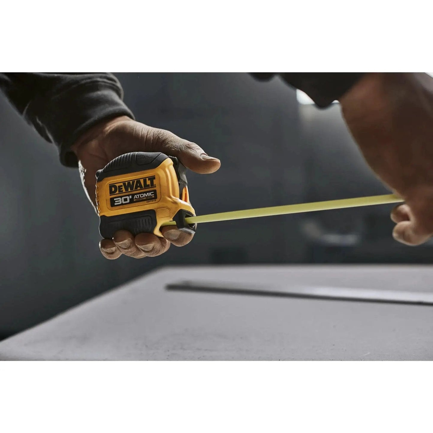 Person using Atomic Compact 30 Ft Tape Measure With Finger Brake for Precision and One Hand Quick Measurement on a job site