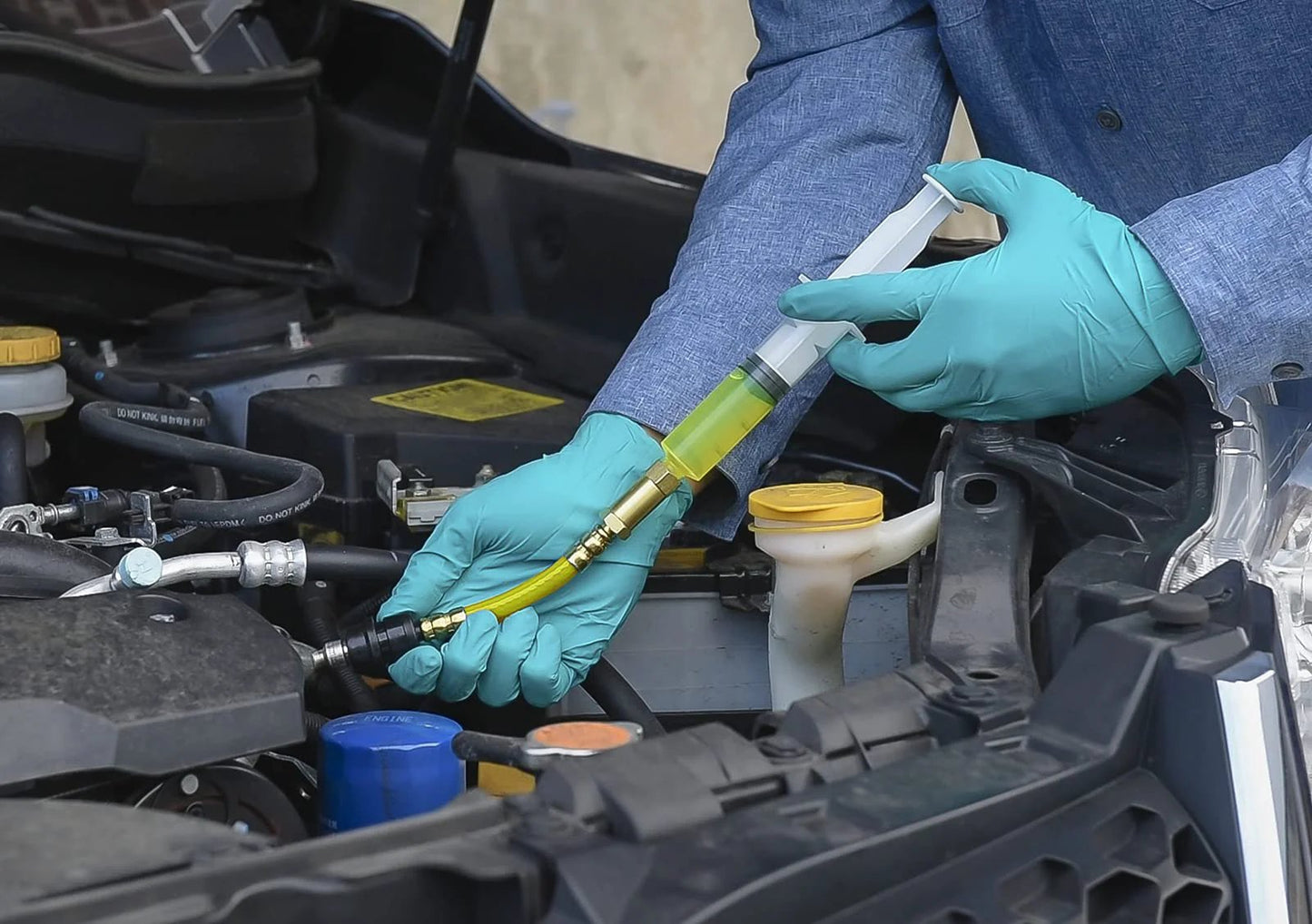 Leak Finder Auto Fluids And Air Conditioning Leak Detection Kit Pro Grade With 1 Oz Dye Injector Syringe UV Light R134A Hose Coupler Made In USA For Quick Easy And Accurate Vehicle Leak Detections For Pro Shops And DIY Maintenance With UV Visibility, being used on a vehicle.