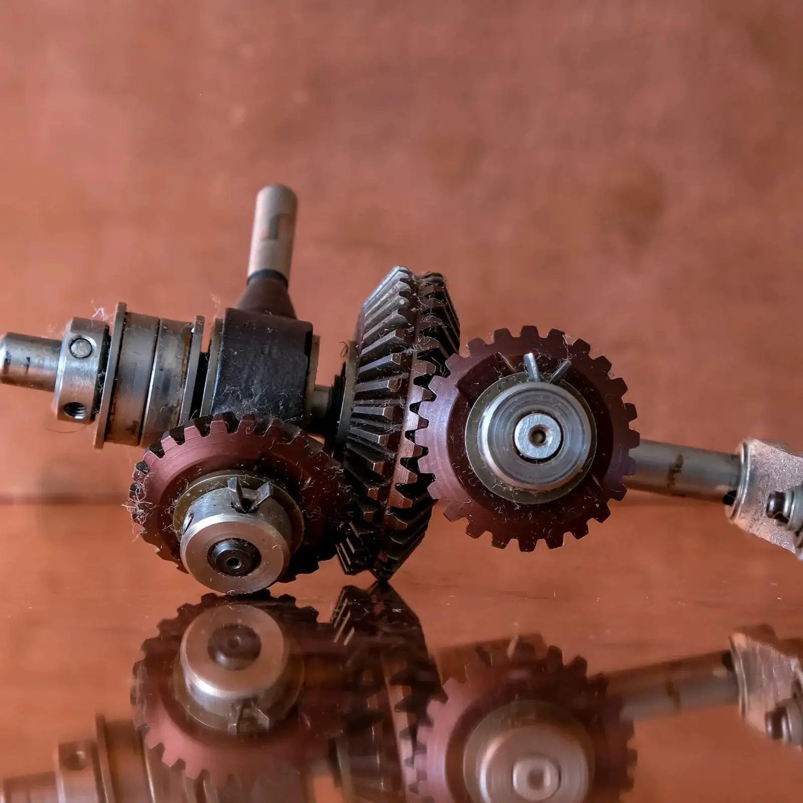 Close-up of Bevel Gear Set 1 Module 1 To 1 20 Teeth 5mm Bore 90 Degree Pinion 4 Pieces showing interlocking gears on reflective surface.