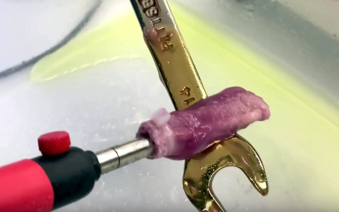 Close-up of tool applying Chrome Plating Kit With Brush System 24K Gold Solution to metal, showing gold finish on a wrench.