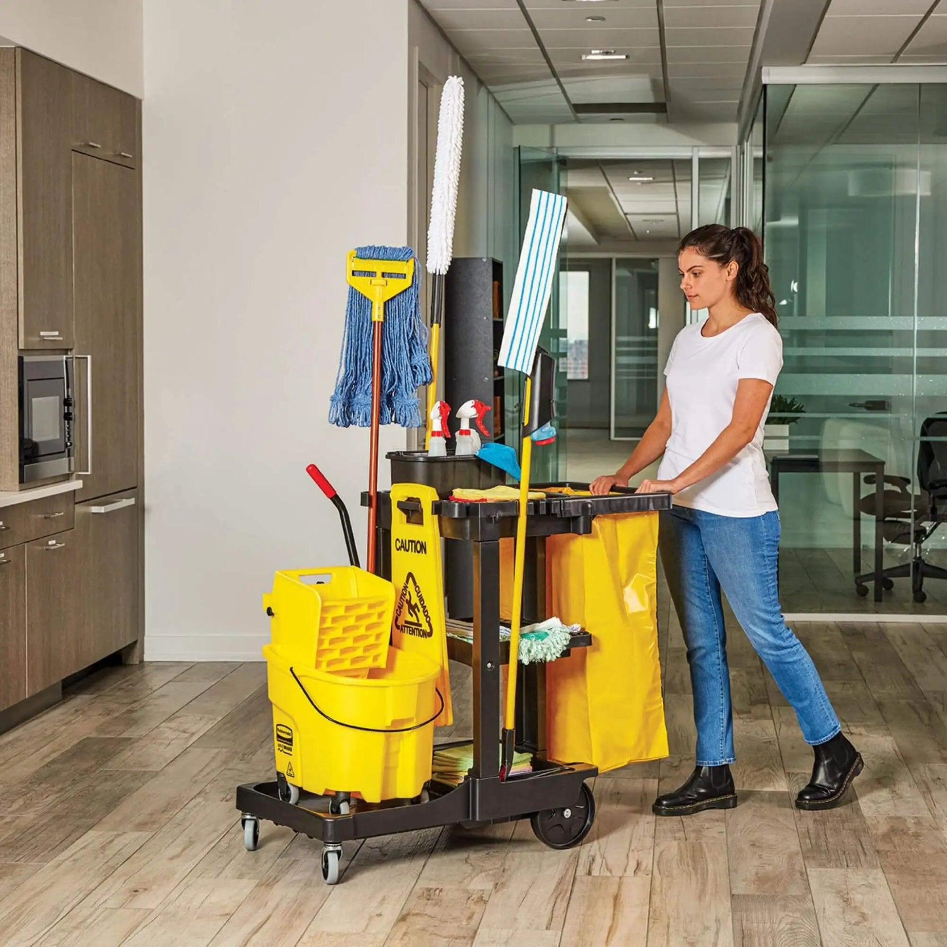 Person pushing Workhorse Commercial Cleaning Cart With 3 Shelf Racks And Wheeled Design Featuring A Zippered Yellow Vinyl Bag Front Platform