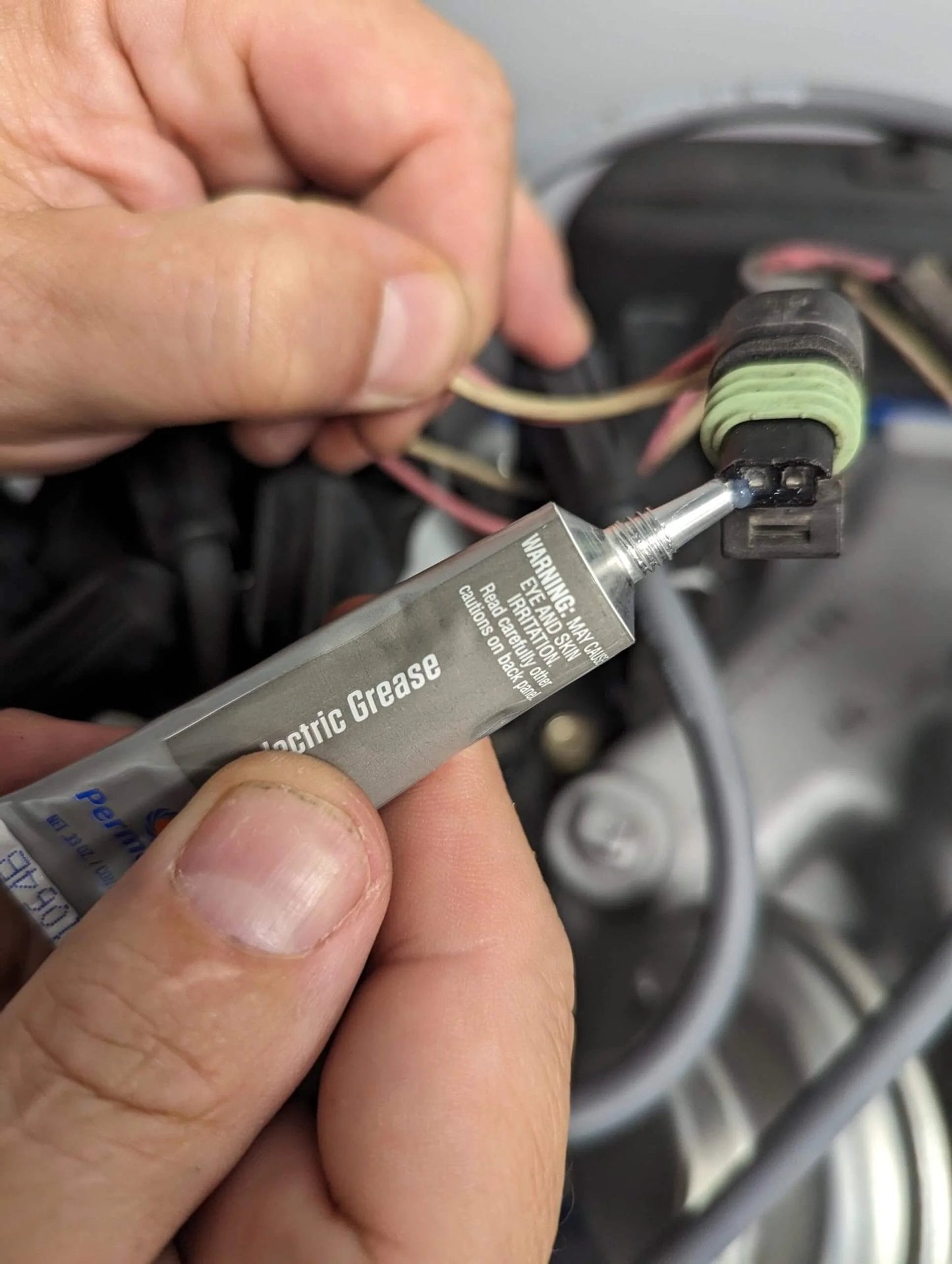 Application of Permatex 81150 Dielectric Tune-Up Grease, 0.33 oz. Tube, Silver on automotive wiring connection for protection.