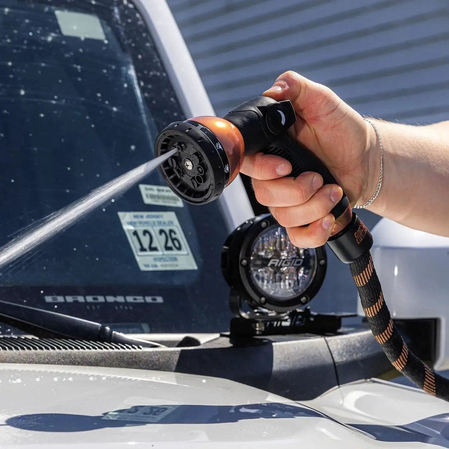 Expandable Garden Hose Copper Bullet With Ten Pattern Thumb Spray Nozzle As Seen On TV 650 PSI in use on a car windshield.