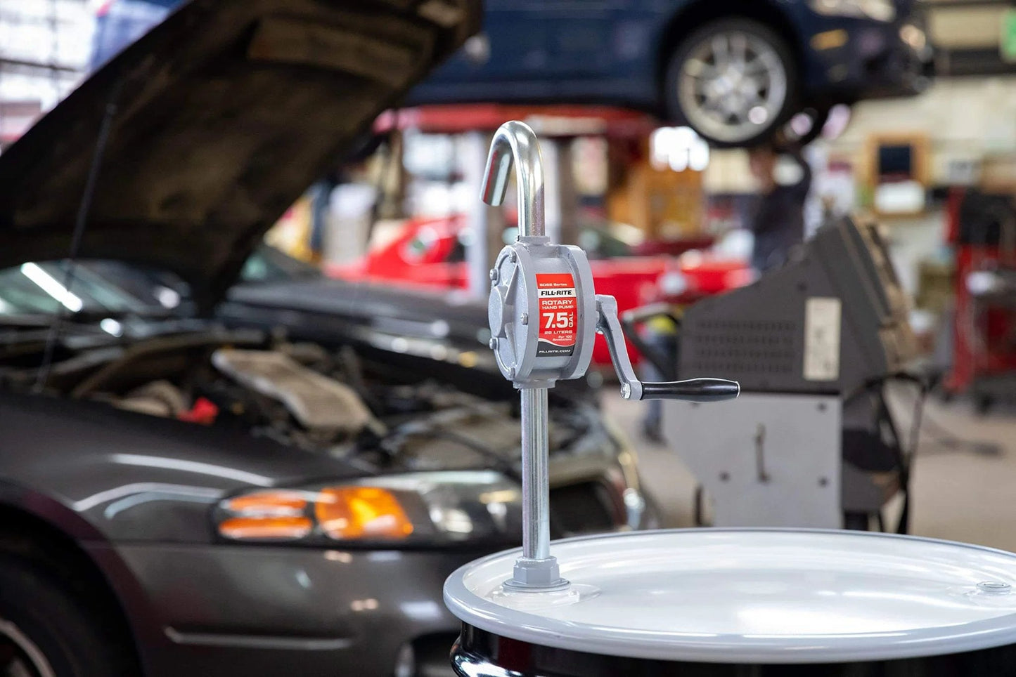 Fill-Rite SD62 Hand Pump Rotary 2-Vane Curved Spout installed on drum in auto workshop
