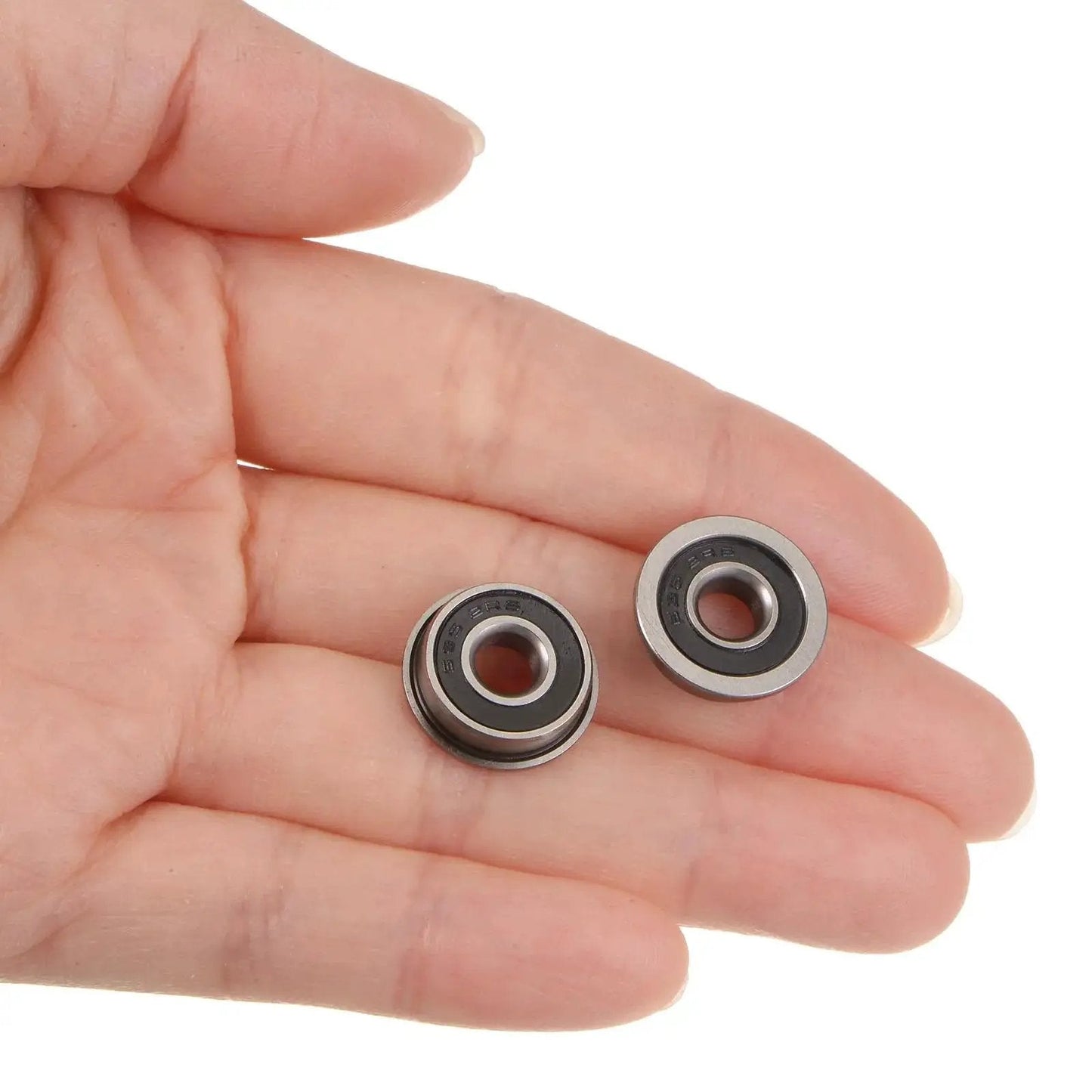 Hand holding two Flanged Ball Bearing F695-2RS 5x13x4mm Double Sealed Chrome Steel ABEC1 Precision Bearings, showcasing size and design.
