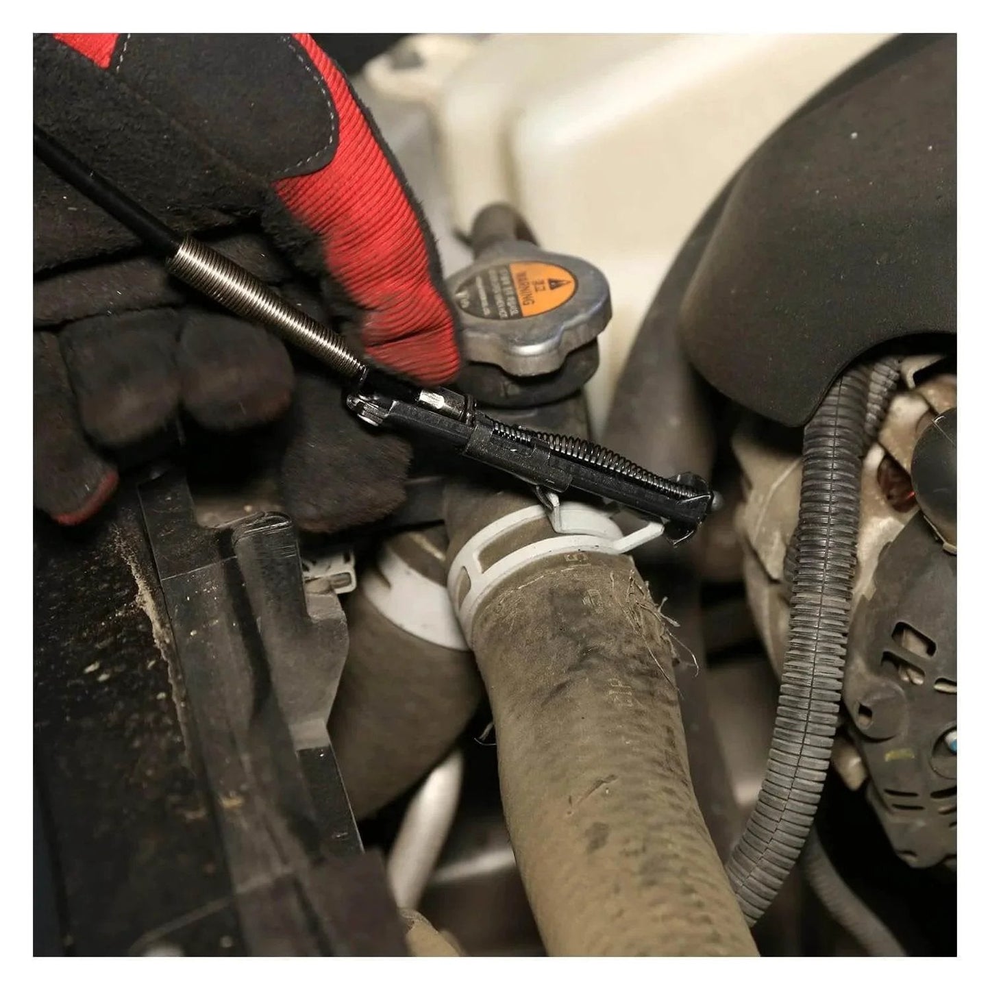 Flexible Hose Clamp Pliers For Automotive Radiator And Heater Hoses Install And Remove Spring Clamps In Hard To Reach Areas Flexible Cable Design With Multi Position Lock For Hands Free Use In Tight Engine Compartments being used to remove a clamp from a hose.