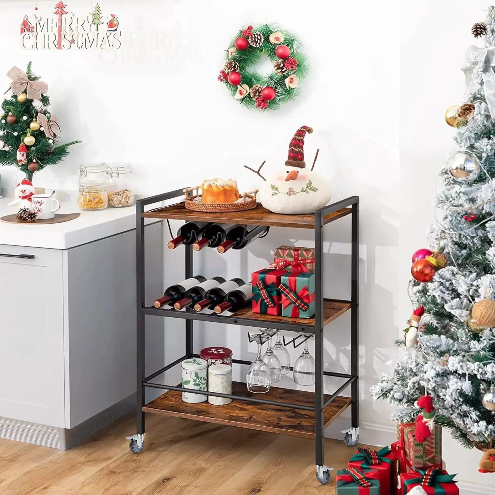 Bar cart with wine bottles, glasses, and snowman decor in festive kitchen scene with Christmas wreaths and tree.