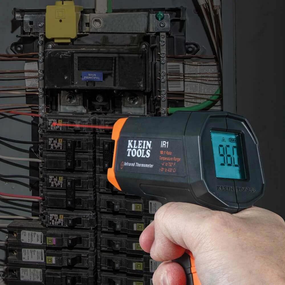 Infrared Thermometer and GFCI Receptacle Tester Kit in use on electrical panel, displaying temperature reading.