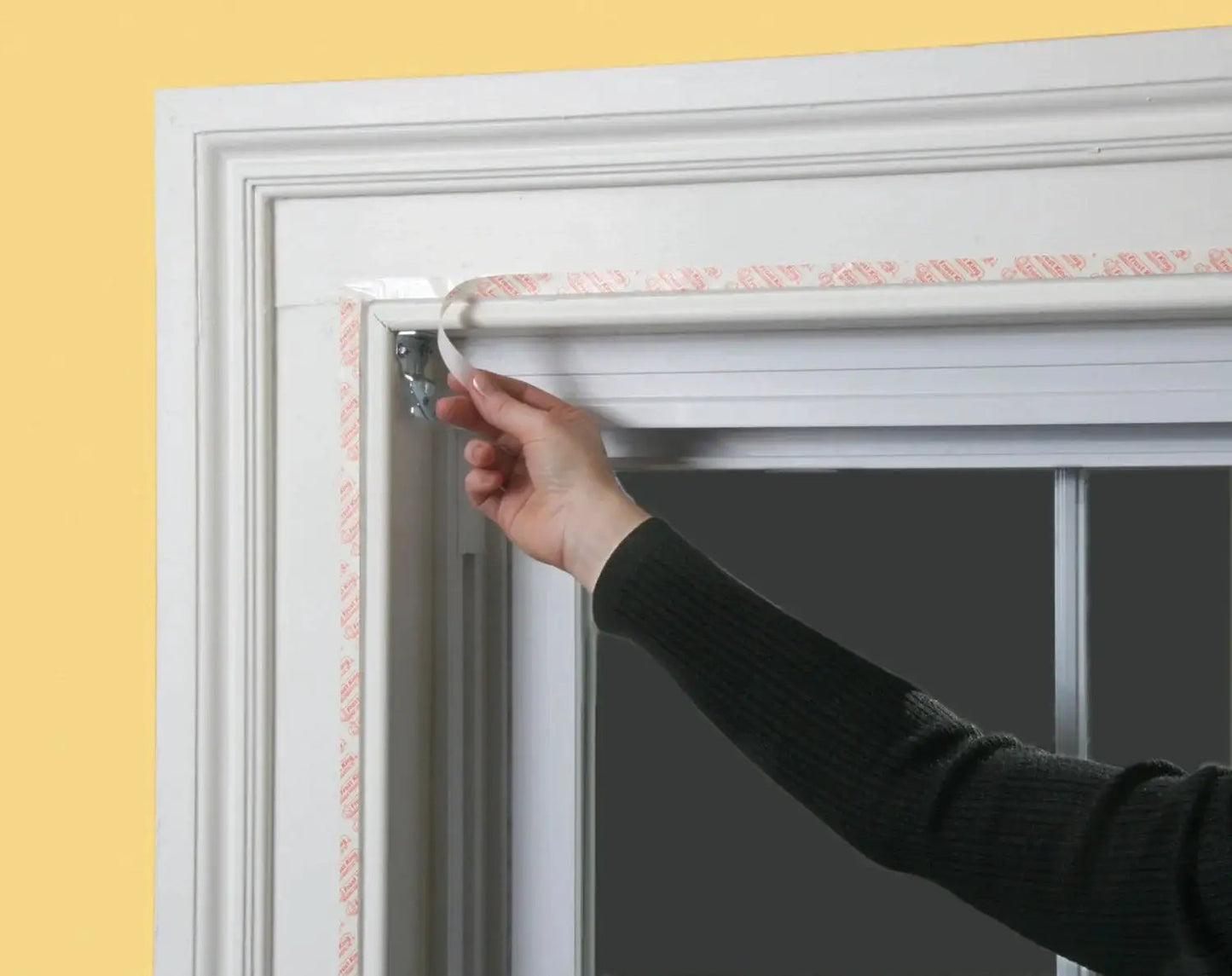 Person applying Indoor Window Shrink Kit For 42 To 62 Inch Windows Clear 9 Pack Insulation Film to window frame