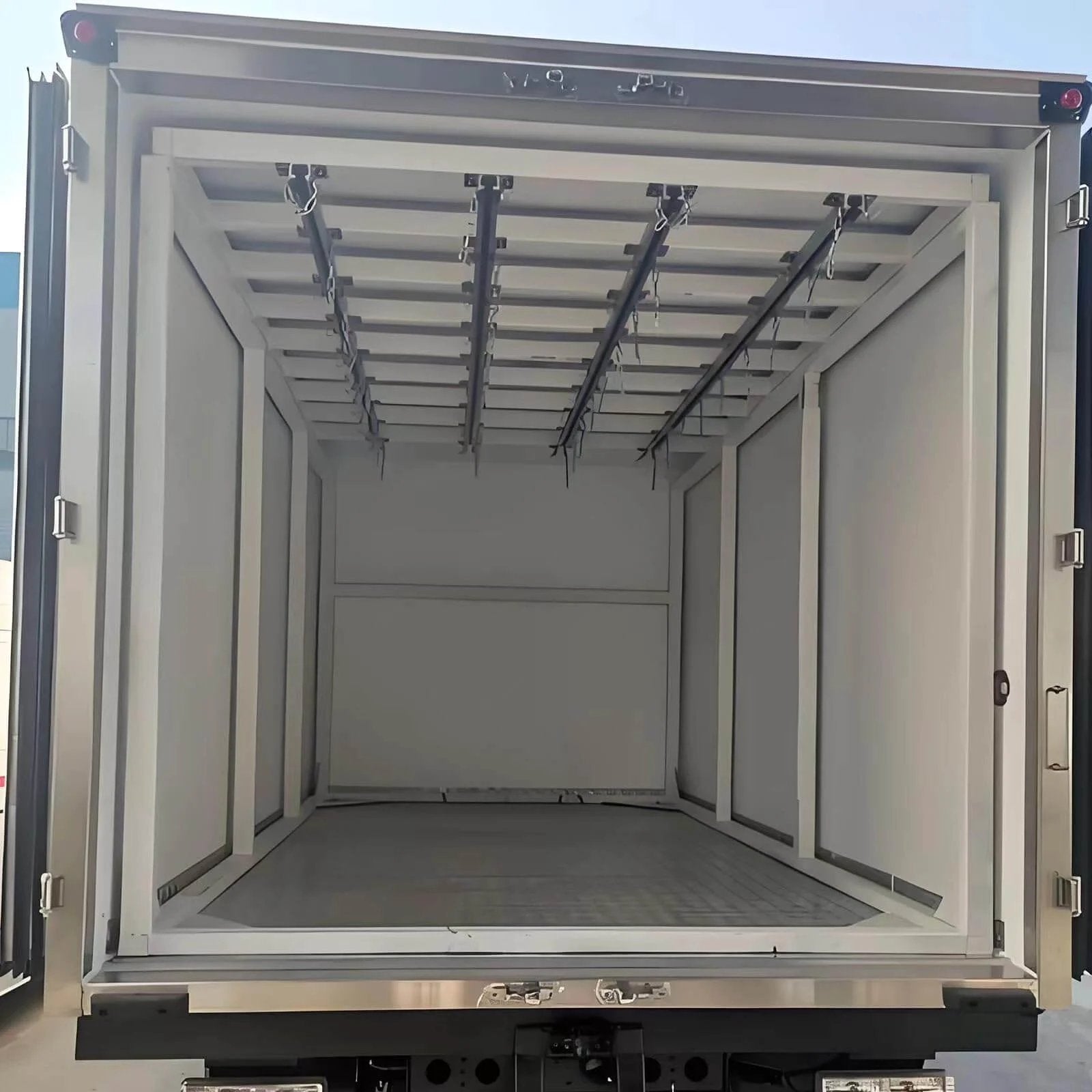 Rear view of an empty industrial container truck showing interior rails for heavy load transport and smooth silent sliding material handling.