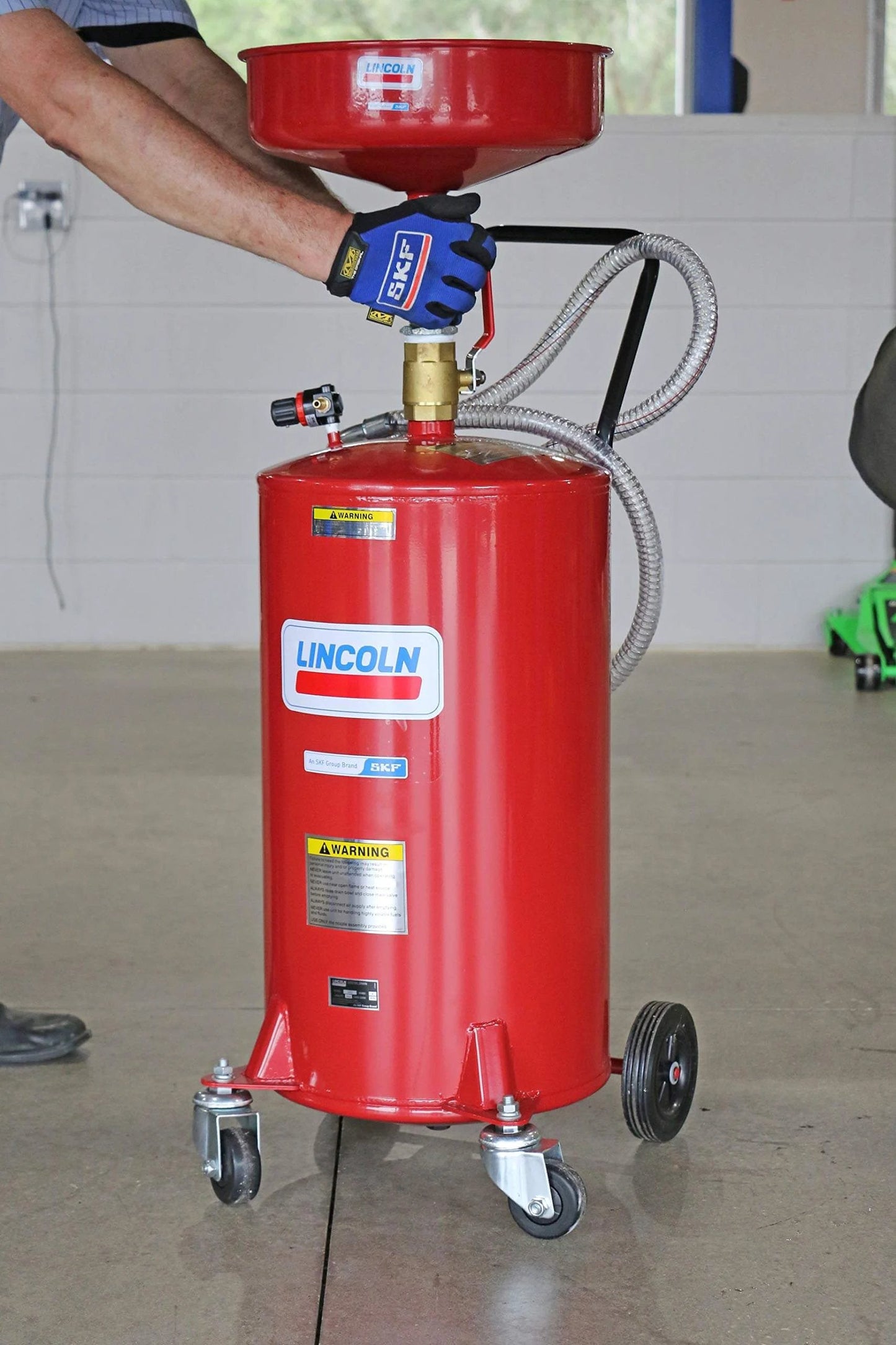 Operator using Lincoln 3601 Pneumatic 18 Gallon Pressurized Fluid Drain and Evacuation Tank, 45-72" Adjustable Funnel Height, 150 PSI, Red.