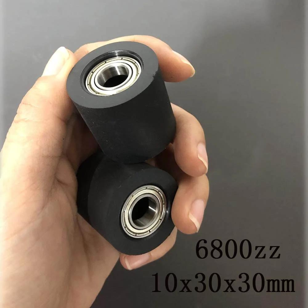 Hand holding two black rubber 6800zz bearings, size 10x30x30mm, for mechanical systems and automation.