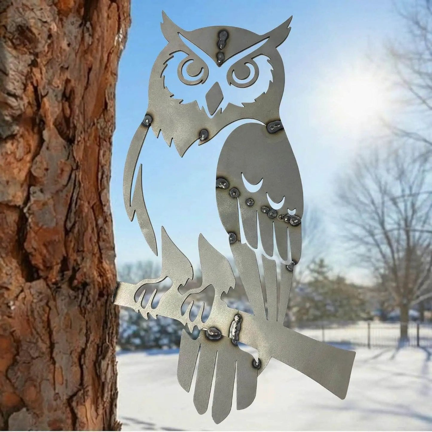 Metal owl decor from Owl Welding Practice Kit For Beginners By ElaraBerry, attached to tree in outdoor setting with snowy background.