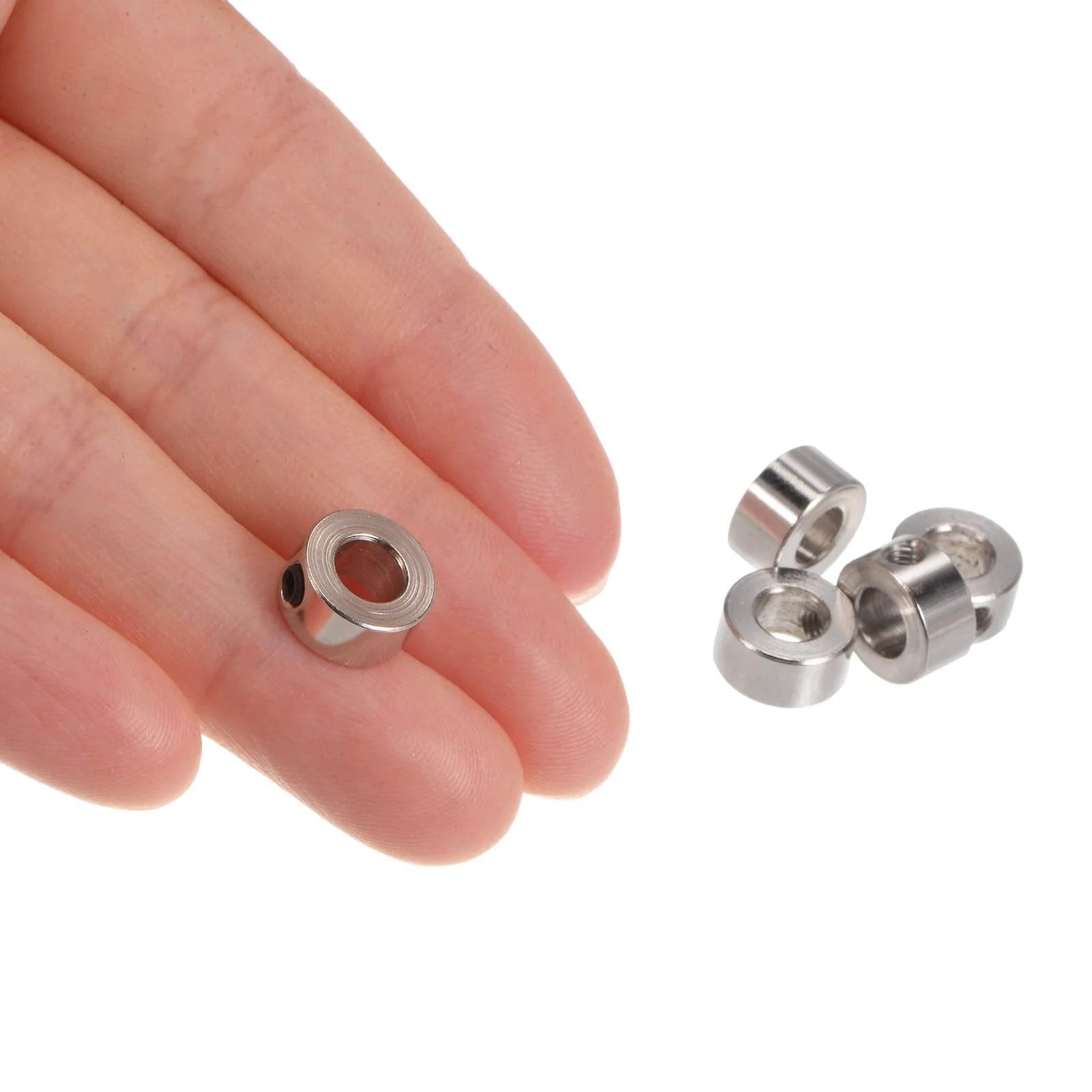 Close-up of a hand holding one of the 10pcs Set Screw Collars 5.05mm Bore Shaft Collars, with four more visible, 10mm OD, nickel-plated.
