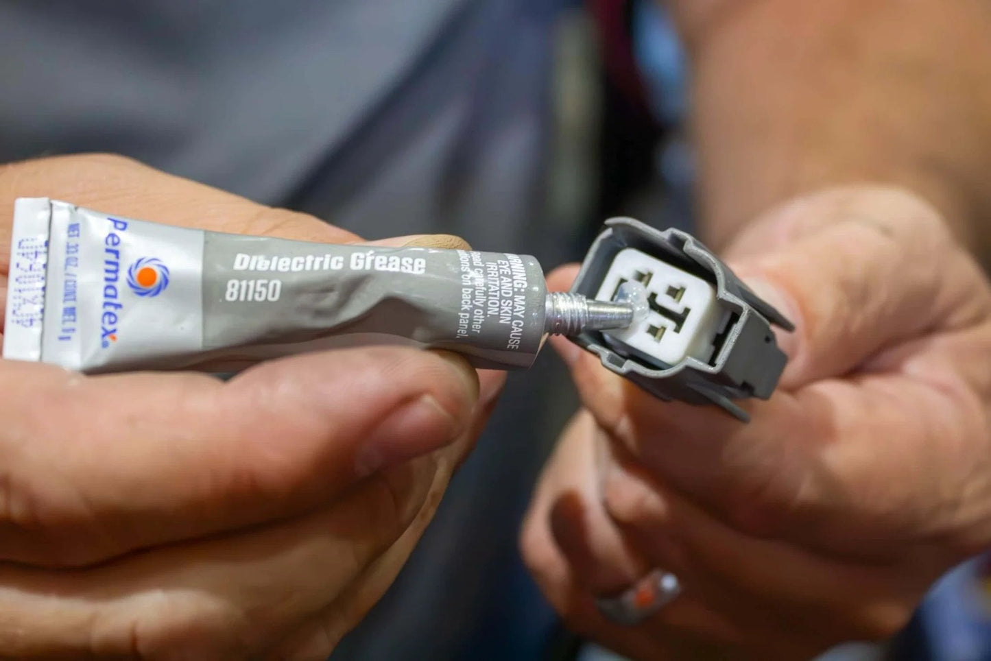 Applying Permatex 81150 Dielectric Tune-Up Grease, 0.33 oz. Tube, Silver to electrical connector in hand.