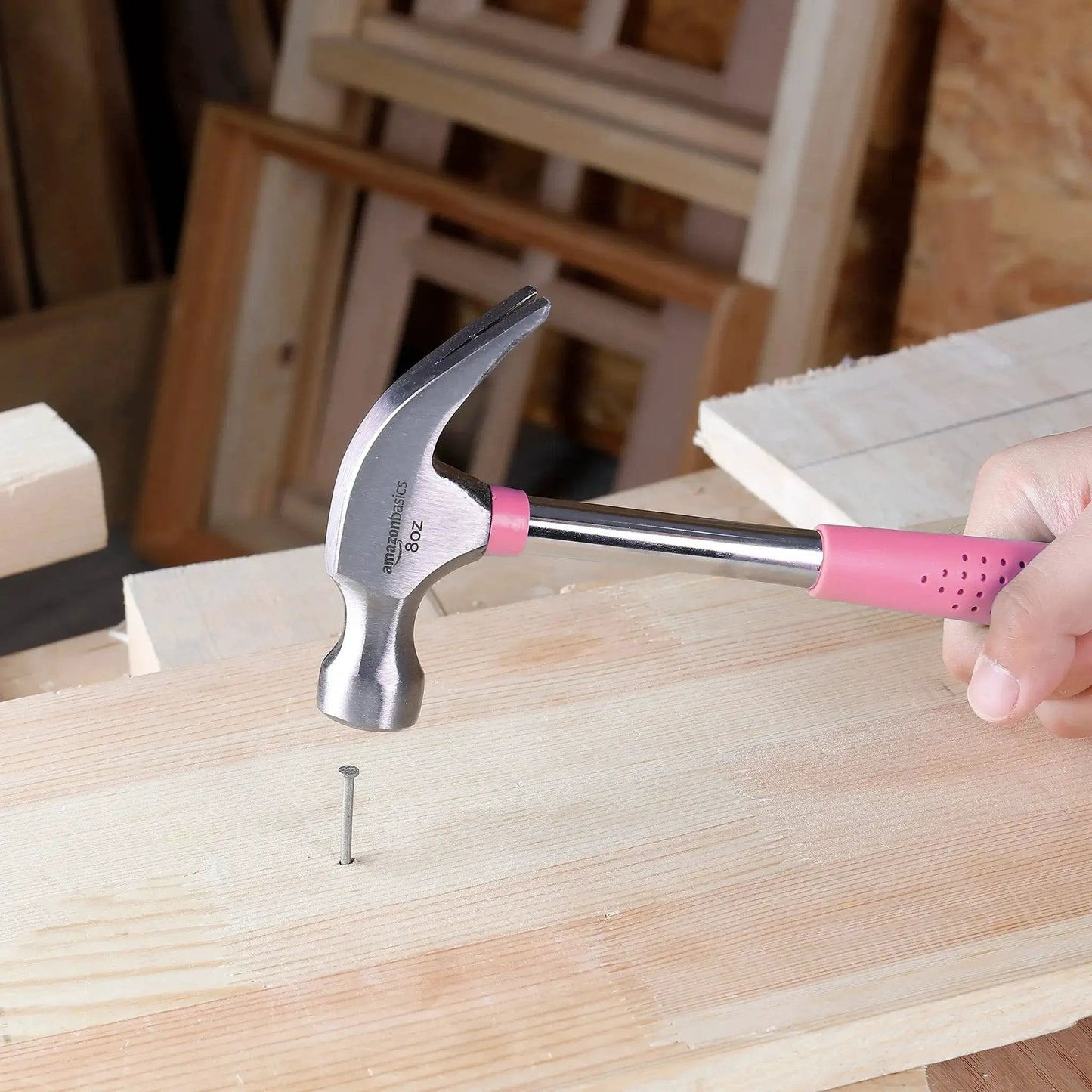 8 oz claw hammer with a shock-absorbing non-slip pink grip used for driving a nail into wood with durable steel head and claw