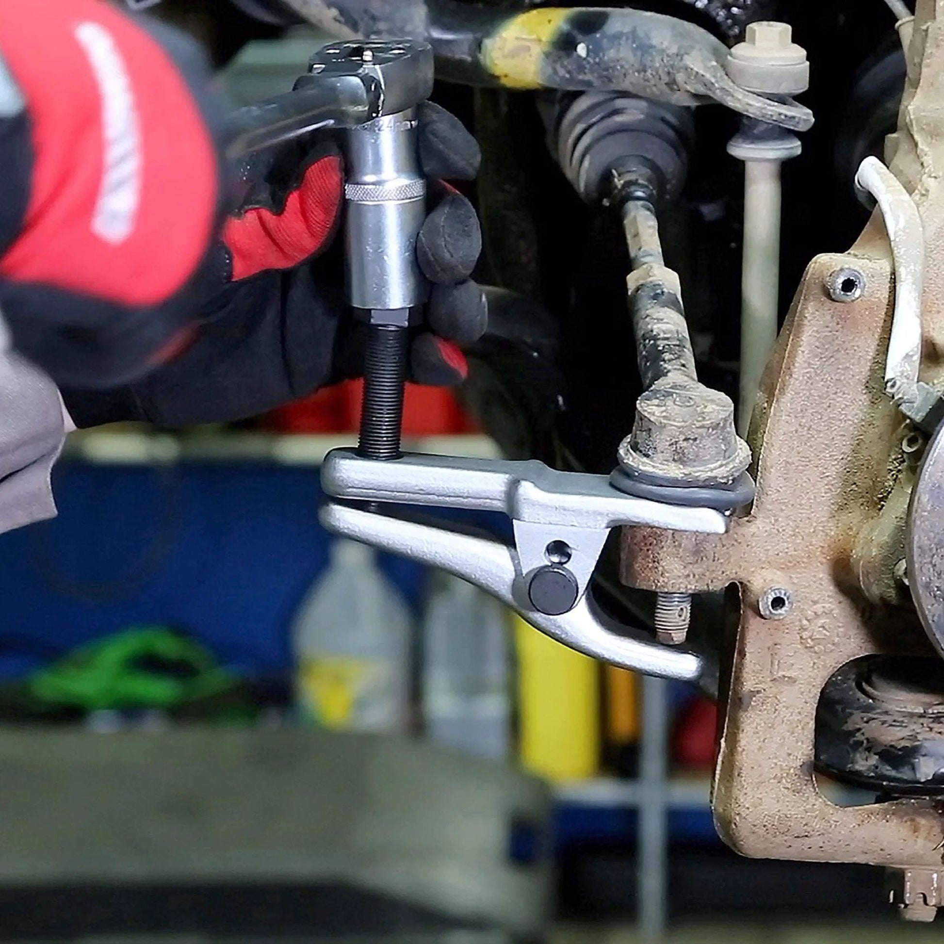 Mechanic using 26554 Front End Service Kit with Pitman Arm Puller on vehicle suspension