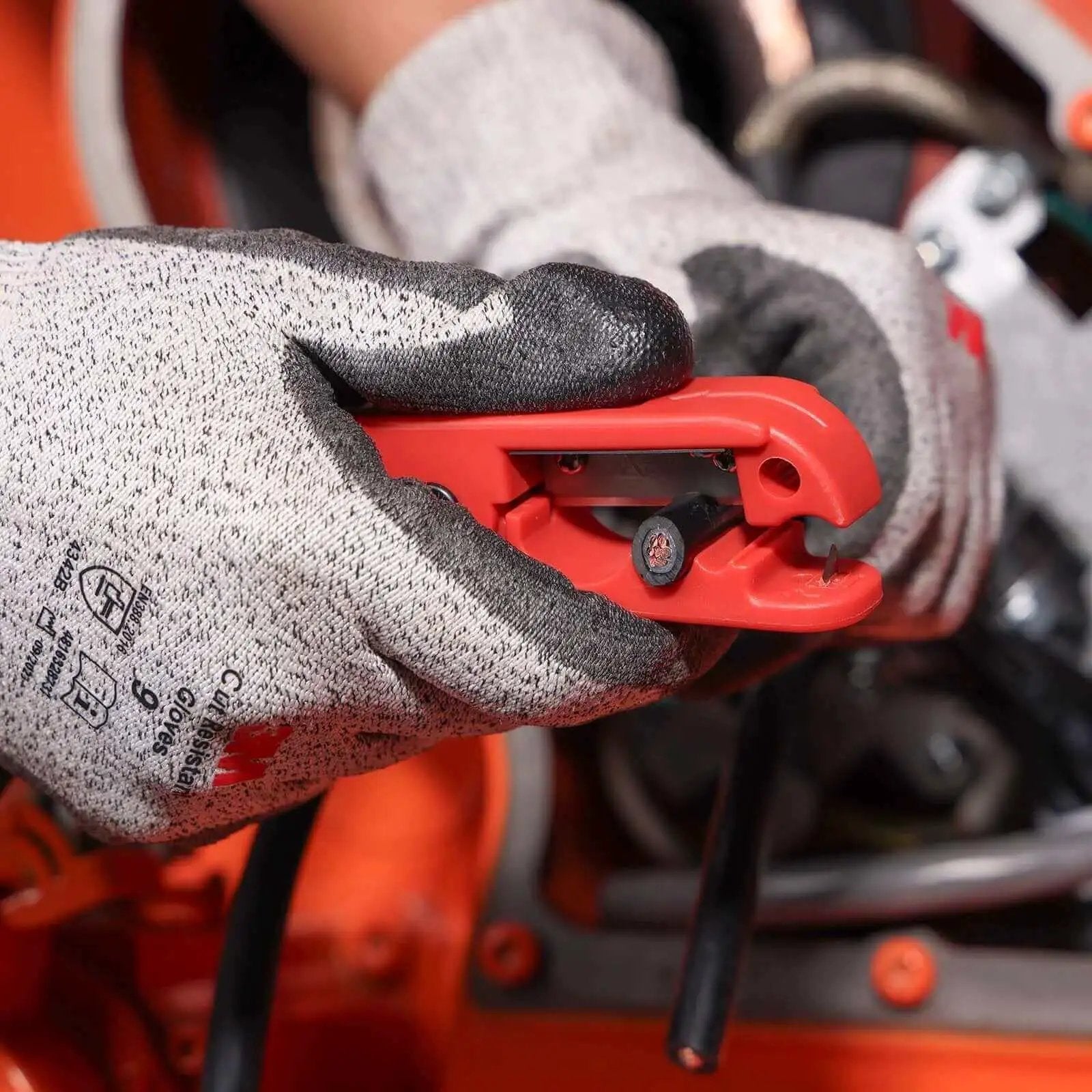 Person using Cable Stripper for AWG 12 to 4/0 Round Cables With Radial Cutting Design on black cable, wearing protective gloves.