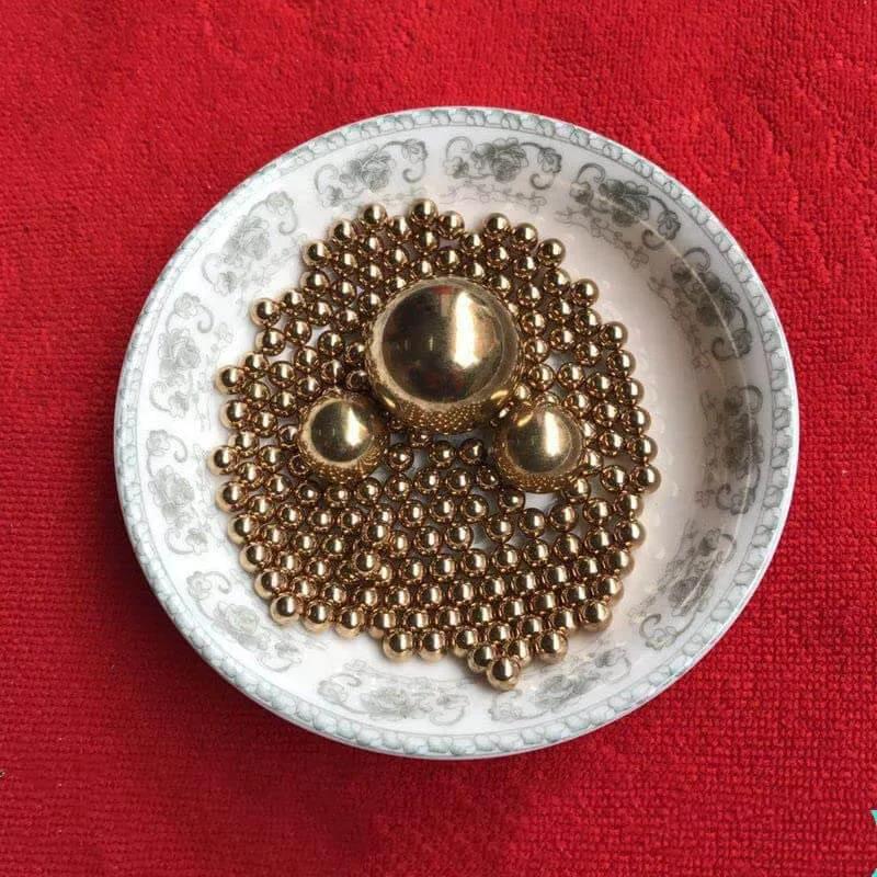 12mm 50pcs Solid Pure Copper Balls - Brass Ball Bead displayed in a decorative bowl on a red background