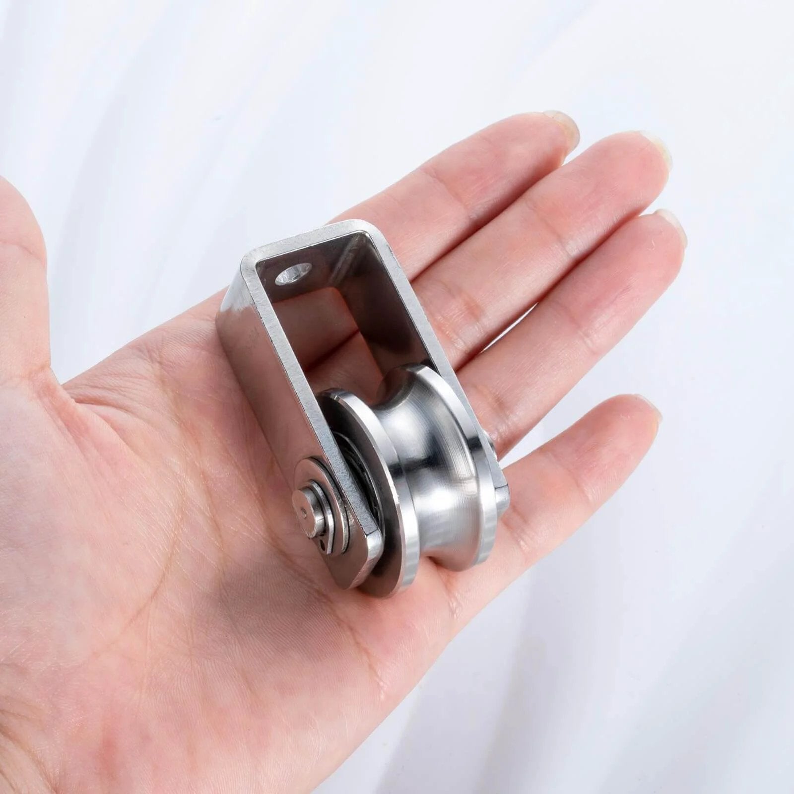 Dual-bearing cable pulley wheel set for rope systems, wall or ceiling mounted, quiet operation, stainless steel, in hand view.