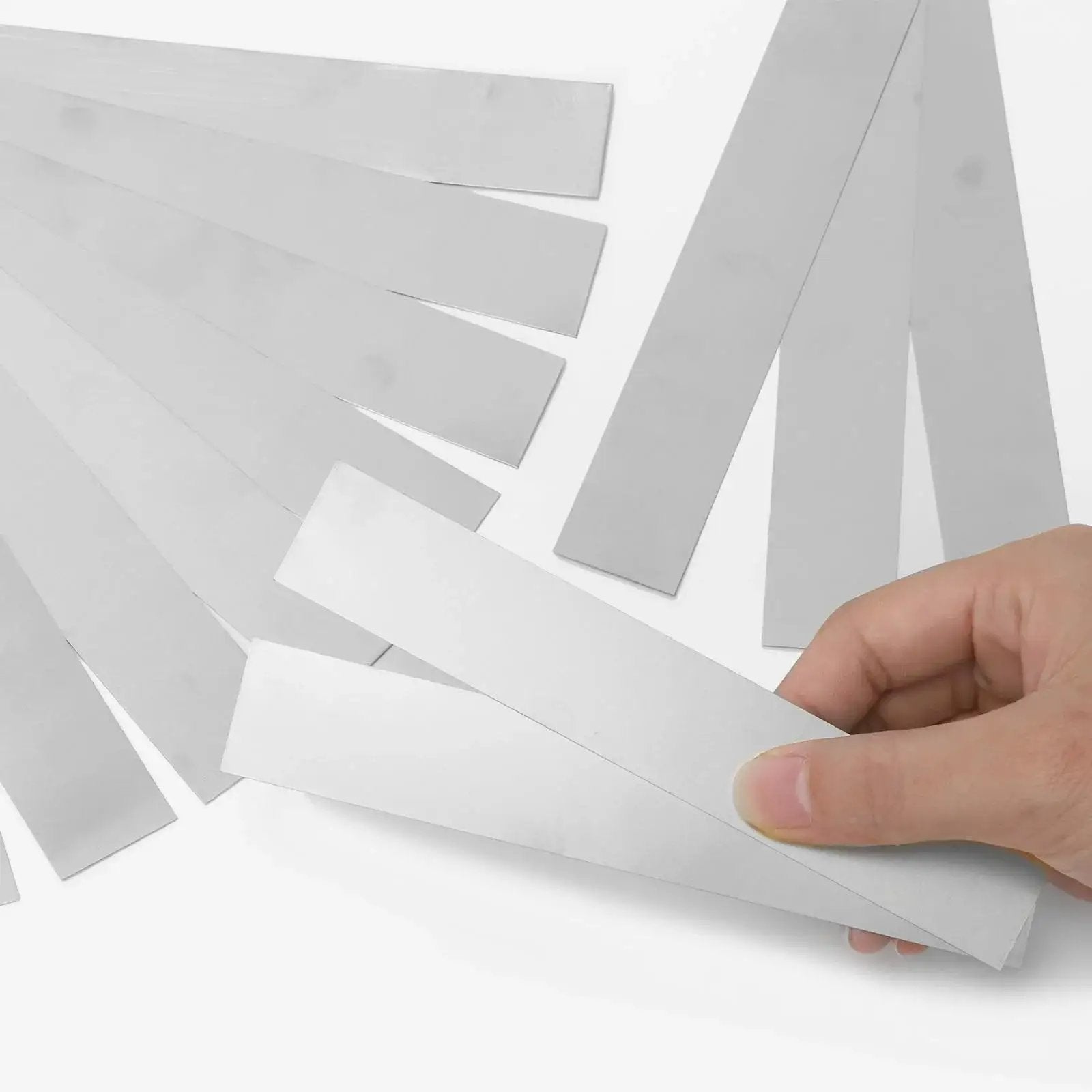 Hand holding Stainless Steel Shim Stock Strips Set 10 Pieces 1 Inch Wide By 6 Inches Long 0.012 Inch Thick Pro Grade 304 Silver Metal