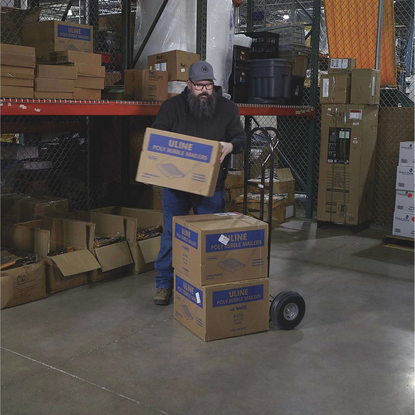 Person using a Steel Pneumatic Hand Truck Dolly - 600-Lb. Capacity, 10in. Tires, Powder-Coat Finish in a warehouse.