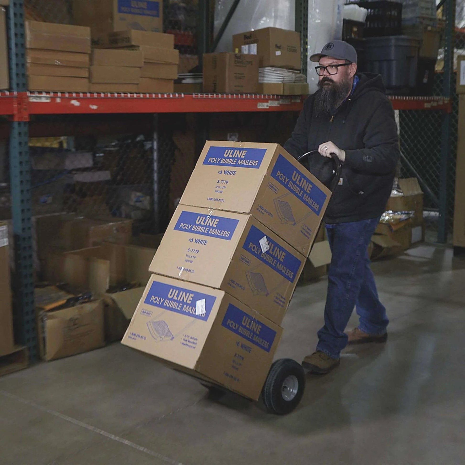 Person using Steel Pneumatic Hand Truck Dolly - 600-Lb. Capacity, 10in. Tires, Powder-Coat Finish to transport boxes in warehouse