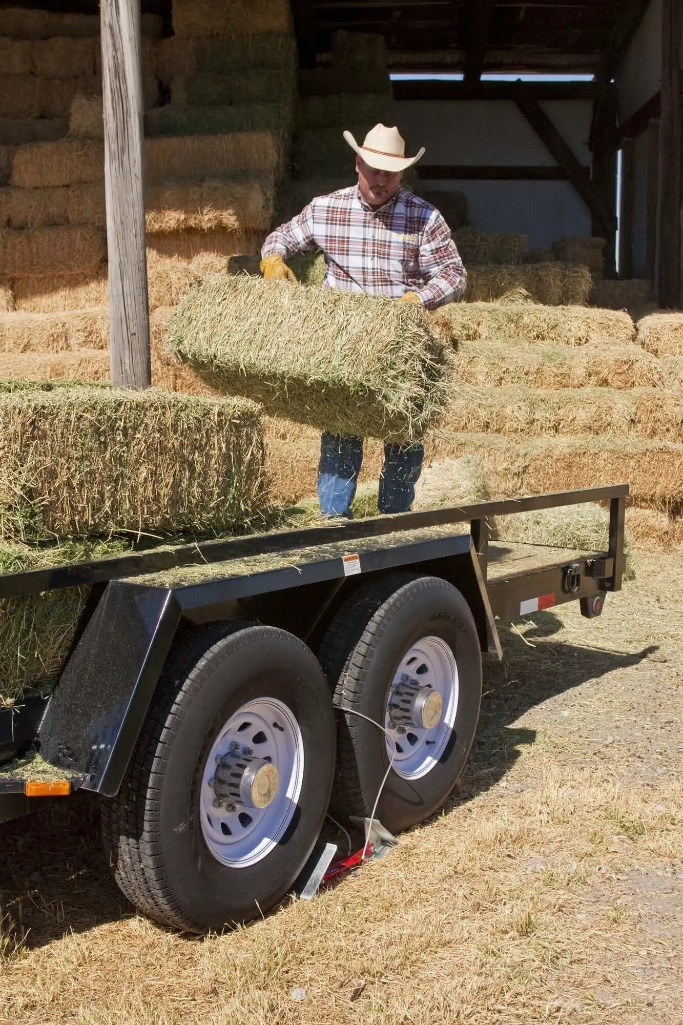 OneStep Wheel Chock Double Pack For Tandem Axle Trailers And RVs, 16 To 24 Inch Long under a loaded hay trailer