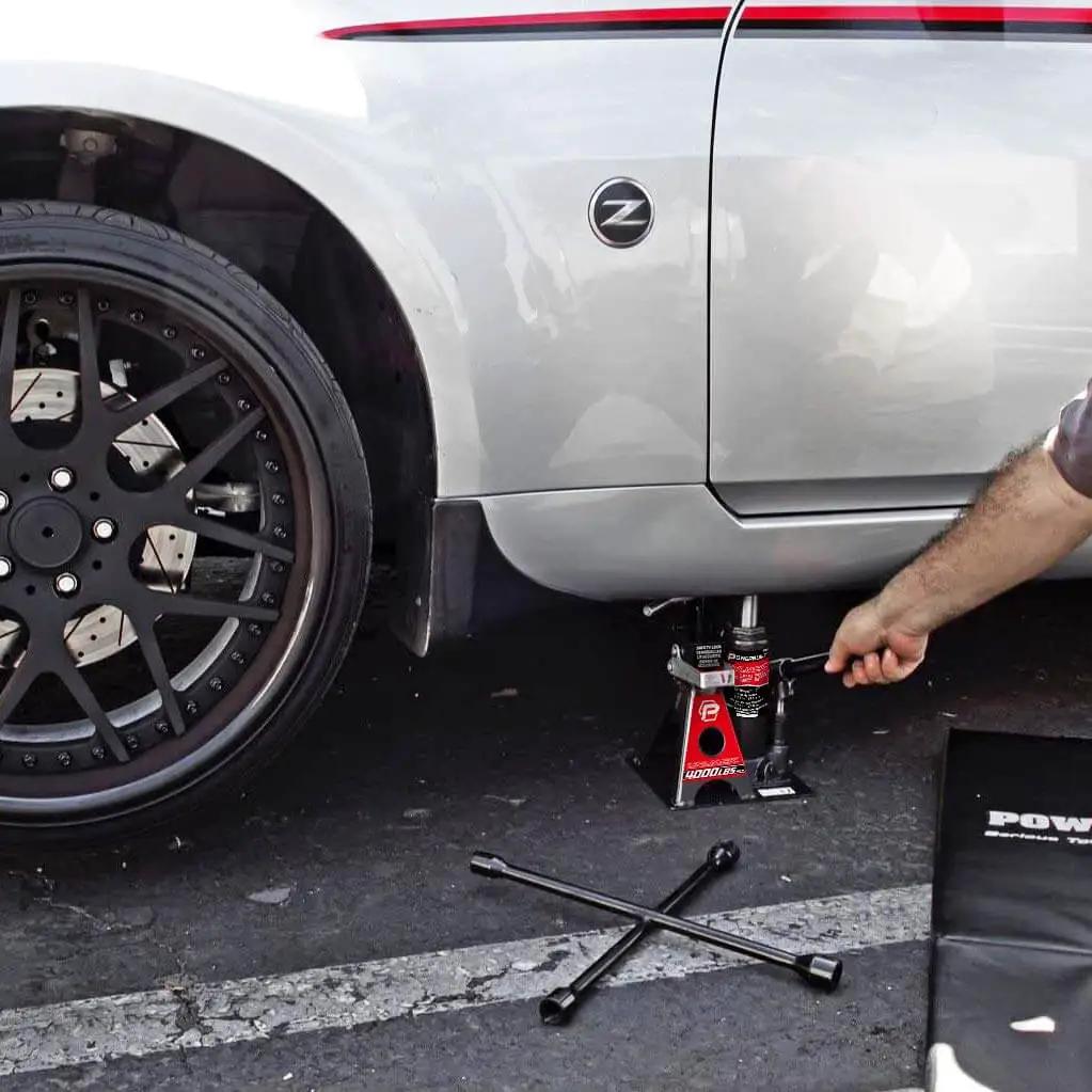 2 Ton UniJack Combination Hydraulic Bottle Jack And Jackstand In One Unit compactly lifting a car, showing stability and portability.