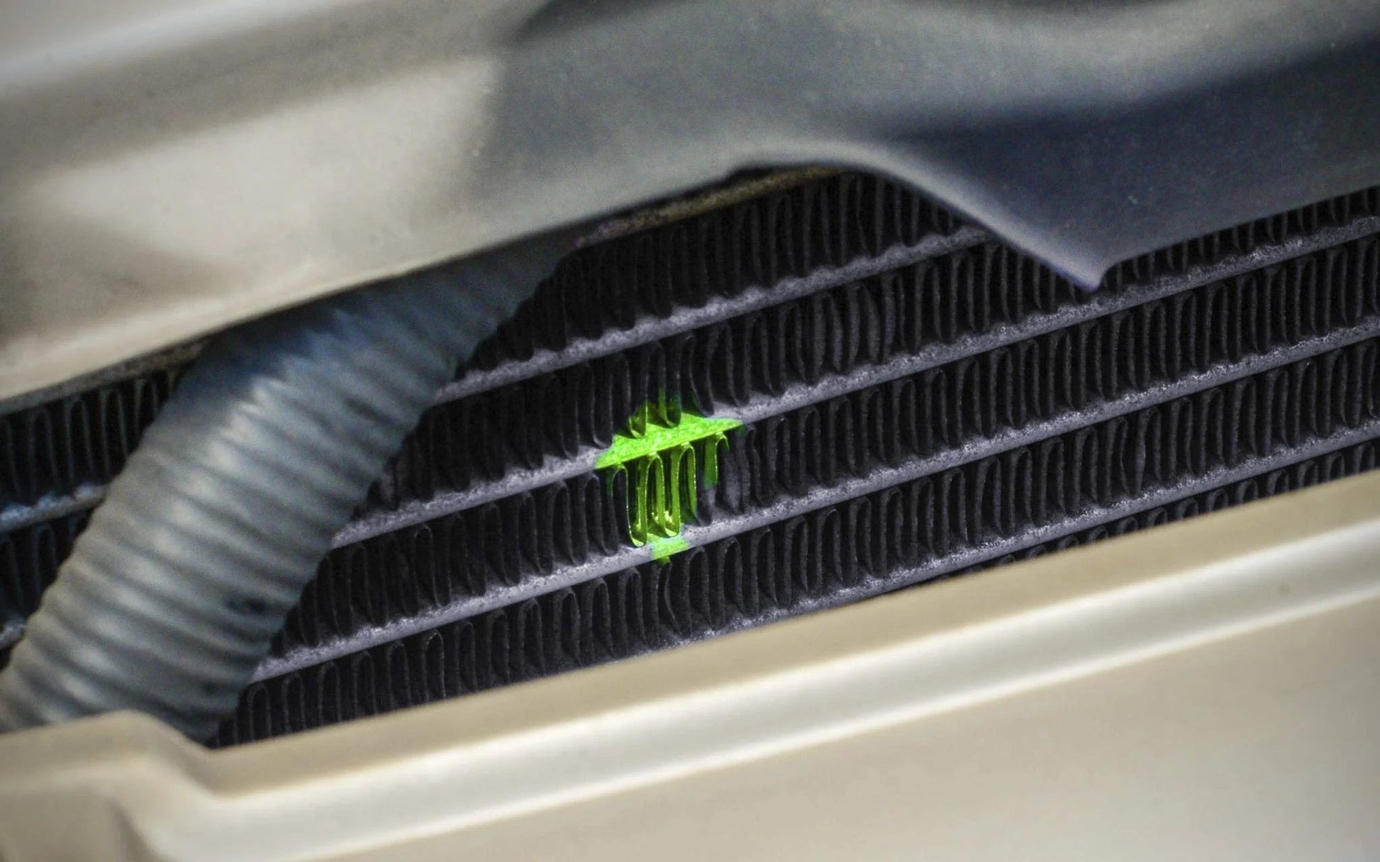 Bright Ultraviolet Automotive Leak Detection Dye For Radiators Hoses Heater Cores And Water Pumps 1Oz Fluorescent Dye Bottle glowing on a radiator.
