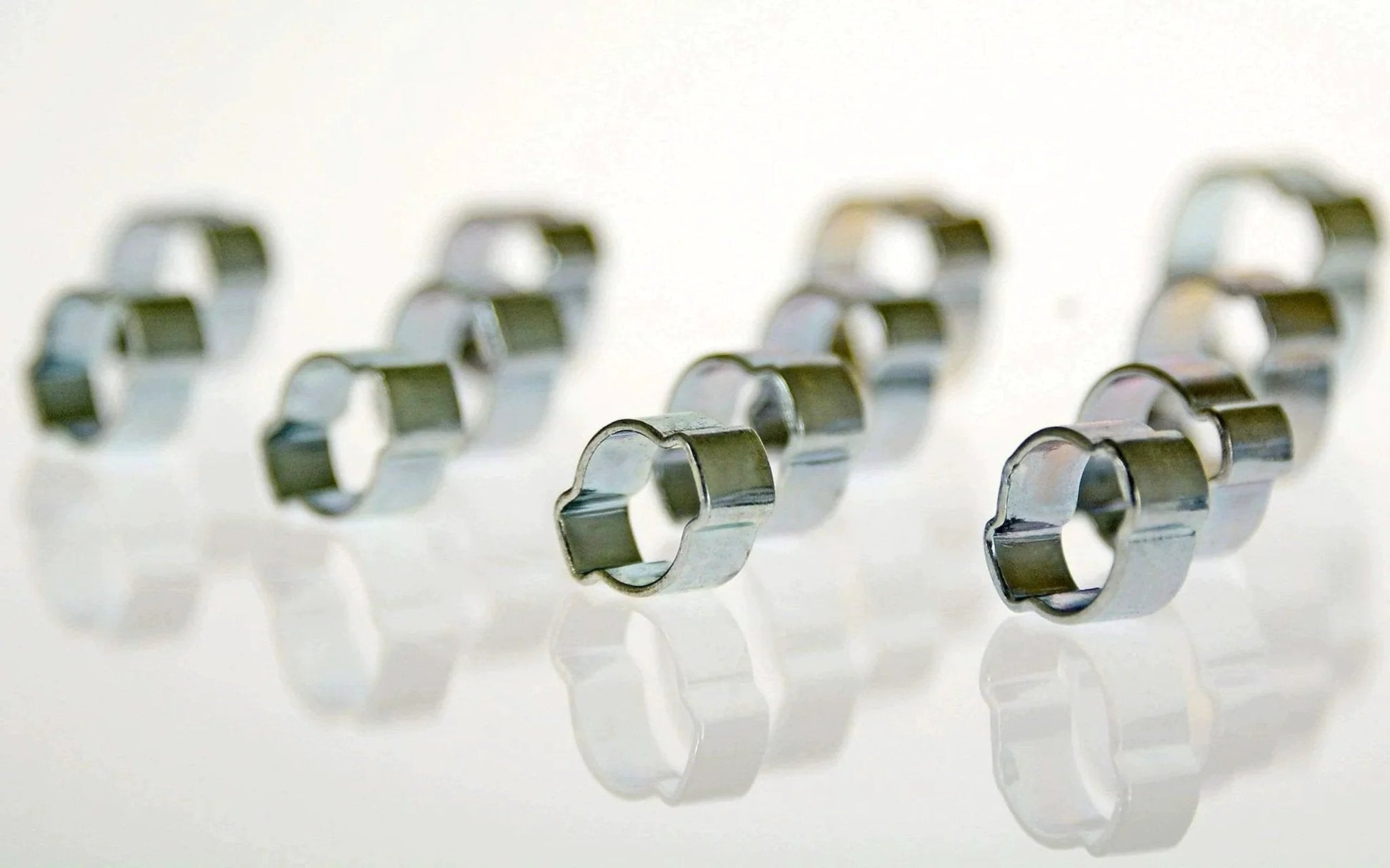 Close-up of zinc-plated steel clamps from Swordfish Two Ear Hose Clamp Assortment 125 Piece Kit By Swordfish Tools, showing smooth deburred edges.